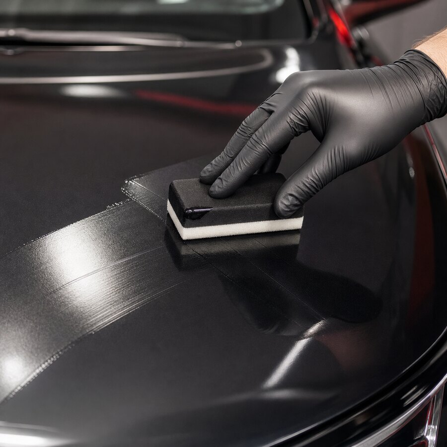 Applicator spreading ceramic coating on car paint